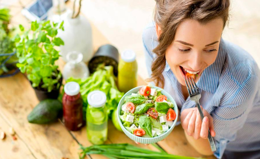 Mujer feliz comiendo ensalada casa tratamiento nutrigenético