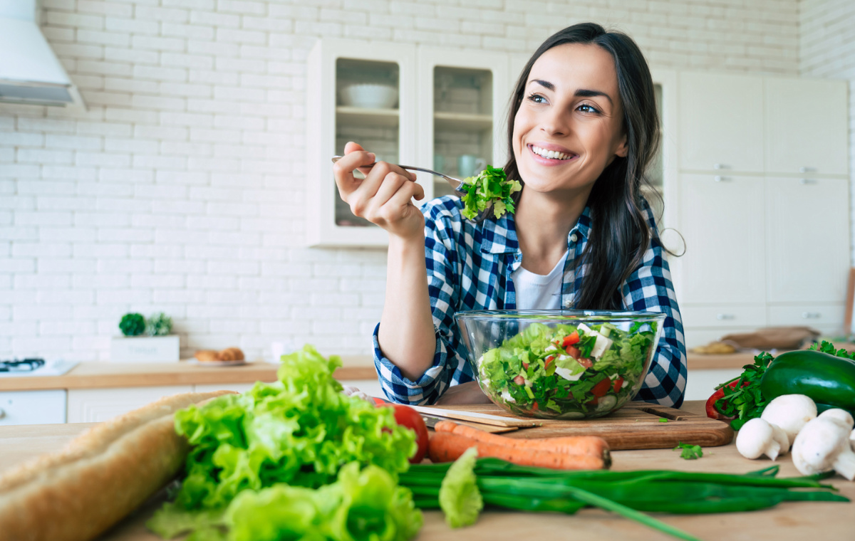 Mujer saludable come ensalada vegana en cocina tratamiento nutrigenético